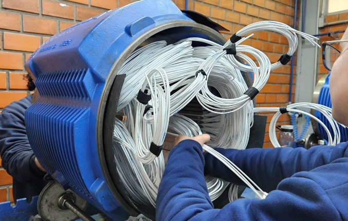 Motor elétrico do tipo molhado durante processo de bobinagem, evidenciando a utilização de fios encapsulados para proporcionar o trabalho submerso diretamente em água.